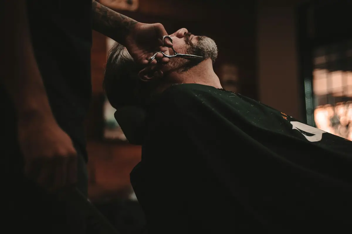 A barber tending to a customer in a busy barbershop